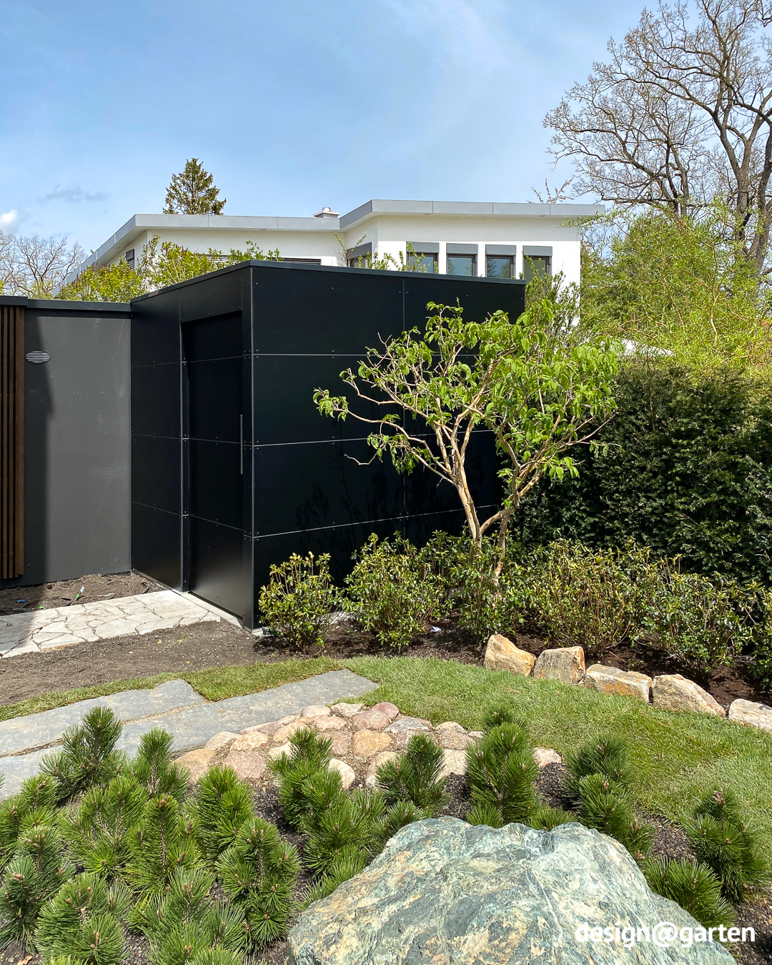 Caseta de jardín de diseño en negro junto a una villa de alta calidad diseñada por un arquitecto.